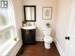 Bathroom featuring a white arched window, dark wood-finish flooring, and a white toilet - 