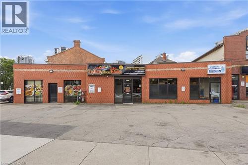 Brick commercial building with multiple storefronts and a paved parking area - 239 York Boulevard, Hamilton, ON 
