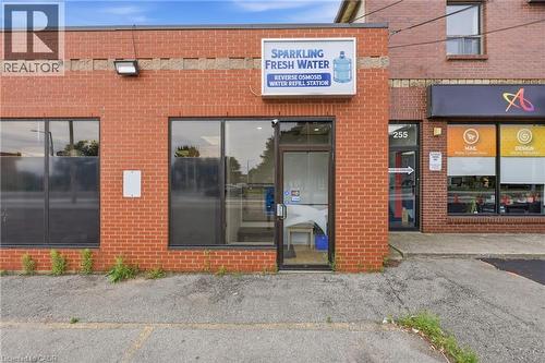 Brick-clad commercial storefront featuring prominent display windows and a glass entry door - 239 York Boulevard, Hamilton, ON 