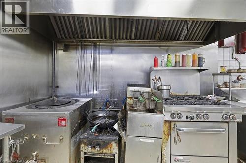 Commercial kitchen featuring stainless steel surfaces and a large overhead ventilation hood - 239 York Boulevard, Hamilton, ON 
