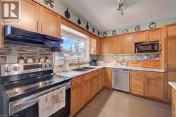 Bright kitchen featuring light wood cabinetry, a mosaic tile backsplash, stainless steel appliances, a double basin sink, and a large window - 
