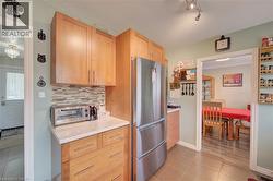 Kitchen featuring natural wood cabinetry, a mosaic tile backsplash, and a built-in stainless steel refrigerator - 