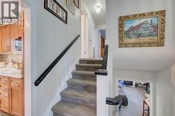 Carpeted staircase with a black handrail and white newel post - 