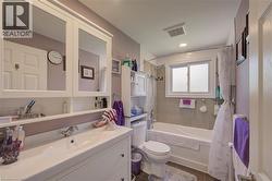 Bathroom featuring a white vanity with integrated sink, dual mirrored medicine cabinets, and a white bathtub with tiled surround - 