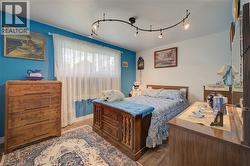 Bedroom featuring a bright accent wall, track lighting, and wood-finish flooring - 