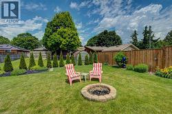 Expansive backyard featuring a stone-ringed fire pit, manicured lawn, and mature perimeter trees - 