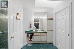 Bathroom featuring a vanity with an integrated sink, green countertop, and mirror with overhead lighting - 