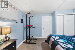 Bedroom featuring light blue walls, wood-finish flooring, a paneled door, and sliding closet doors - 