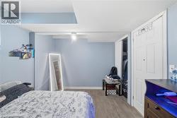 Room featuring light blue walls, wood-finish flooring, a white ceiling with exposed beams, recessed lighting, and a bi-fold closet door - 