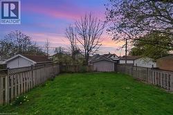 Expansive backyard featuring a green lawn, wood privacy fencing with lattice top, and garden beds - 