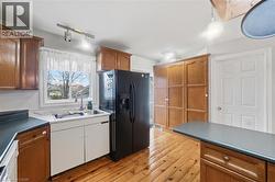 Kitchen featuring wood-finish flooring, wood cabinetry, built-in storage, a stainless steel sink, and track lighting - 