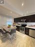 Contemporary kitchen featuring dark wood cabinetry, stainless steel appliances, and light-toned, veined tile flooring - 181 Thaler Avenue, Kitchener, ON 