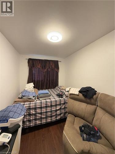 Interior room featuring wood-finish flooring, white walls, and a window with dark fabric drapes - 181 Thaler Avenue, Kitchener, ON 