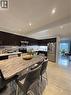 Open-concept kitchen featuring dark wood cabinetry, stainless steel appliances, recessed ceiling lighting, a large island with a stone countertop, and tile flooring - 181 Thaler Avenue, Kitchener, ON 