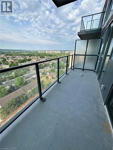 Private balcony featuring a textured gray concrete surface, clear glass railings with black metal frames, frosted glass privacy panels, and a high-rise urban backdrop - 2782 Barton Street E, Hamilton, ON 