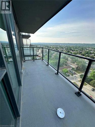 Expansive balcony featuring a textured concrete surface, clear glass railing with black posts, and broad cityscape scenery - 2782 Barton Street E, Hamilton, ON 