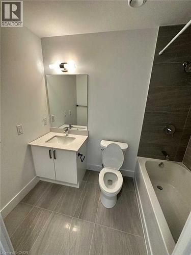 Bathroom featuring a white vanity with integrated sink, a rectangular mirror, and a contemporary light fixture - 2782 Barton Street E, Hamilton, ON 
