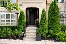 Stone facade featuring a dark paneled entry door, concrete steps with black railing, and a black exterior light fixture - 