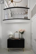 Two-story entry featuring an upper-level balcony with black wrought iron railing, a brass chandelier, and white-painted walls - 