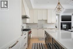 Contemporary kitchen featuring a large center island with a white countertop, extensive white cabinetry, and stainless steel appliances - 
