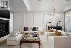 Living area featuring a black-framed fireplace, recessed lighting, and a gold-finish chandelier - 