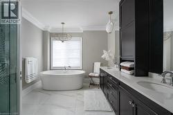 Freestanding oval soaking tub with floor-mounted tub filler, set against a window with horizontal blinds - 