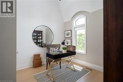 Office space featuring light wood-finish flooring, an arched window, and vaulted ceiling - 