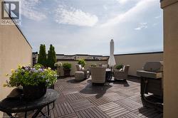 Expansive rooftop terrace featuring modular wood-finish decking, a low perimeter wall, and architectural planting elements - 