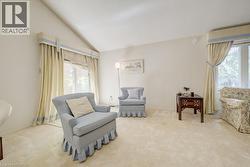 Vaulted ceiling living space featuring plush light-toned carpeting and large windows with custom drapery - 