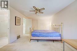 Carpeted room with a ceiling fan, dual bi-fold closet doors, and an open doorway revealing a tiled bathroom with a shower enclosure - 