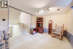 Carpeted room with a staircase featuring a white railing, track lighting, and a patterned wallpaper - 
