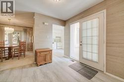 Entryway featuring light-toned flooring, textured wallcovering, and a glass-paneled door with an integrated blind - 