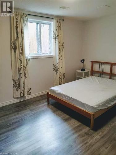 Bright room featuring a window with patterned drapes, wood-finish flooring, white baseboards, and a neutral wall color - 389 Tealby Crescent Unit# Lower, Waterloo, ON 