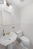 Pedestal sink with brass-finish faucet, white toilet, and wall-mounted mirror - 