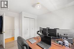 Office space featuring wood-finish flooring, white walls, built-in closet with bi-fold doors, and a ceiling-mounted light fixture - 