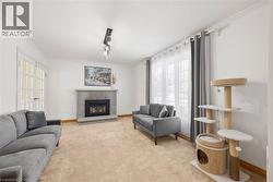 Living area featuring a stone-clad fireplace, French doors, and substantial crown molding - 
