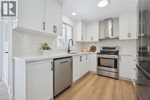 Contemporary kitchen featuring white cabinetry with black hardware, white countertops, and a white subway tile backsplash - 299 Dale Crescent, Waterloo, ON 