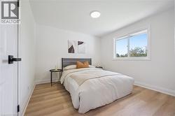 Bright room featuring light wood-finish flooring, white baseboards, and a contemporary flush-mount ceiling light - 