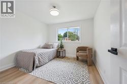 Bright interior room featuring a window overlooking greenery, light-toned wood-finish flooring, and a flush mount ceiling light - 