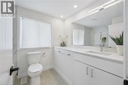 Contemporary bathroom featuring a white vanity with an integrated sink, polished chrome faucet, and expansive wall-mounted mirror - 