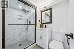 Contemporary bathroom featuring a spacious shower with black-framed glass enclosure, white marble-patterned tile, and two inset shelves - 