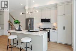Kitchen area, quartz counters, island, staircase to upper level - 
