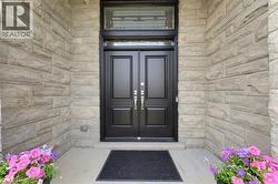 Entryway featuring a black double door with decorative glass transom and sidelights, set within a stone-clad facade - 