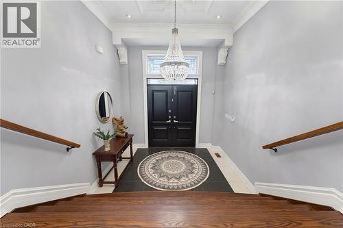 Entryway featuring a double black door with transom window, a prominent crystal chandelier, and dark tile flooring - 38 River Valley Drive, Kitchener, ON 