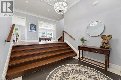 Elegant entry foyer featuring dark wood-finish stairs, dark tile flooring, and a decorative chandelier - 38 River Valley Drive, Kitchener, ON 