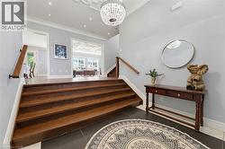 Elegant entry foyer featuring dark wood-finish stairs, dark tile flooring, and a decorative chandelier - 