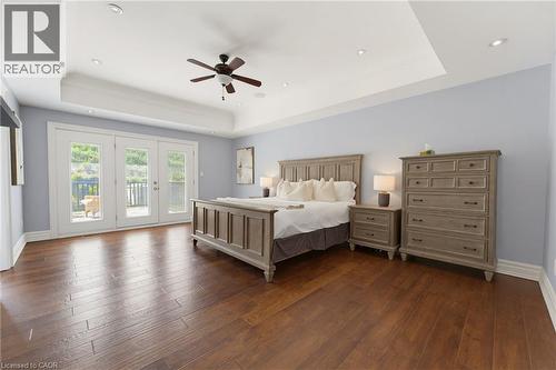 Spacious interior featuring rich wood-finish flooring and a tray ceiling with recessed lighting - 38 River Valley Drive, Kitchener, ON 
