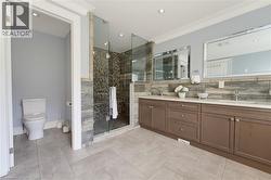 Bathroom featuring a spacious walk-in shower with glass enclosure, dual vanity with quartz countertops, and tile flooring - 