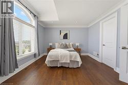 Spacious room featuring wood-finish flooring, a large arched window, recessed lighting, and crown molding - 