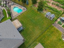 Expansive rear yard featuring a freeform swimming pool with rock features, a paved patio, a wooden deck, and two storage sheds - 